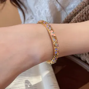 Gros plan détaillé d'un jonc doré de style chinois avec des pétales en émail violet et rose