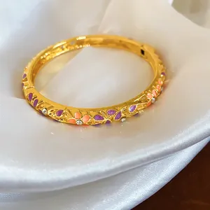 Gros plan sur le jonc doré avec des fleurs en émail coloré et des cristaux