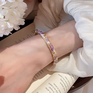 Gros plan d'un jonc en émail doré avec des motifs floraux et des cristaux éclatants.