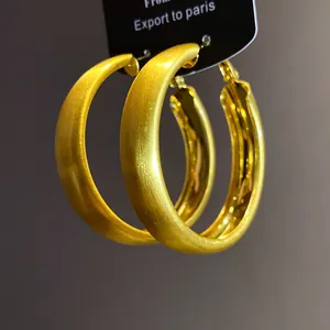 Macro view of minimalist golden hoop earrings with a brushed matte texture finish