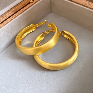 Macro view of matte brushed gold hoop earrings presented in a luxury velvet jewelry box