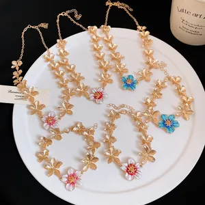 Dettaglio di set gioielli vintage in metallo dorato con ciondoli a fiori smaltati