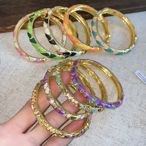 Gros plan sur les motifs floraux colorés en émail sur des bracelets dorés de style chinois.