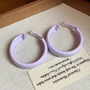 Detail view of light purple spray-painted hoop earrings on a textured background