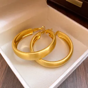 Close-up of elegant brushed gold hoop earrings with minimalist texture design.