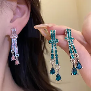 Detailed view of vintage silver needle drop earrings with pink and teal rhinestones.