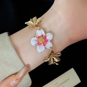 Dettaglio macro di un bracciale a fiori vintage in smalto e metallo su un polso femminile