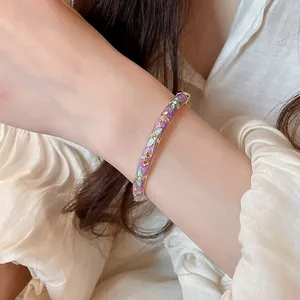 Vue détaillée d'un élégant bracelet jonc en émail violet doré porté au poignet d'une femme
