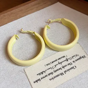 Close-up of matte yellow spray painted hoop earrings with silver pins