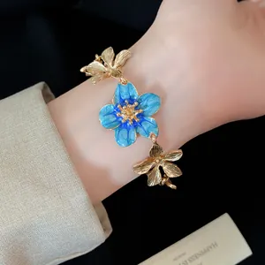 Dettagliata vista macro di bracciale a fiori dorati vintage con petali in smalto blu