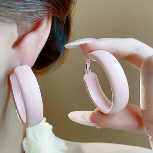 Detailed view of trendy pink thick hoop earrings with smooth spray finish on ear