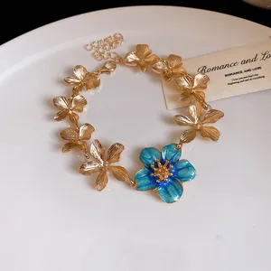 Primo piano di un bracciale vintage in metallo dorato con fiore smaltato blu