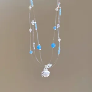 Close-up of ocean-themed necklace with shell, pearl, and blue beads