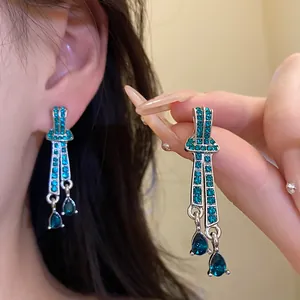 Close-up detail of vintage teal rhinestone water drop pendant earrings worn on ear