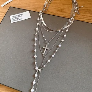 Elegant layered silver necklace featuring pearl beads and a sparkling rhinestone cross pendant