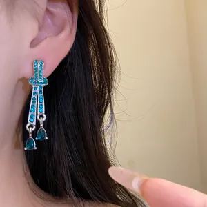 Close-up of vintage silver needle earrings with turquoise rhinestones and teardrops.
