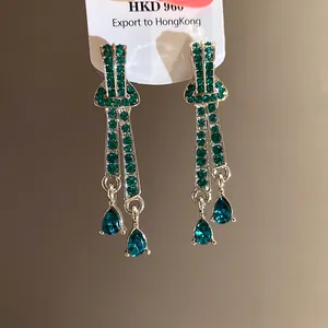 Detailed view of vintage green rhinestone drop earrings with teardrop crystals