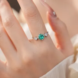 Détail d'une bague réglable délicate avec un zircon central vert en argent brillant