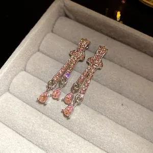 Macro detail of elegant silver dangle earrings featuring pink teardrop rhinestones