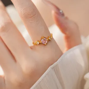 Bague réglable dorée élégante avec un zircon rose carré et des pierres latérales.