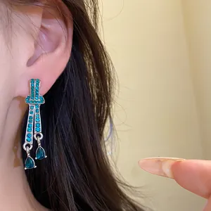 Close-up detail of vintage silver teardrop earrings with elegant teal rhinestones