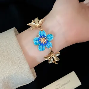 Elegante bracciale floreale vintage con un fiore in smalto blu visto sul polso.