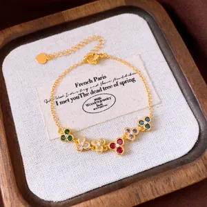 Détail d'un bracelet doré vintage français avec cinq breloques fleurs en zircon coloré