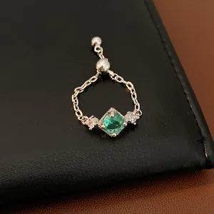 Gros plan d'une bague chaîne argentée ajustable avec zircon vert et pierres latérales