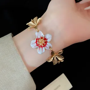Dettaglio ravvicinato di un bracciale floreale vintage con fiori in smalto bianco e rosso