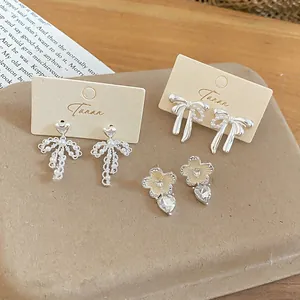 Detailed view of elegant silver bow earrings and pearl heart studs on display cards