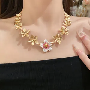 Vista dettagliata dell'elegante collana di fiori d'oro con centro in smalto bianco