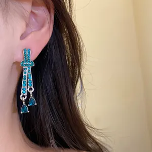 Close-up of elegant vintage silver waterdrop earrings with turquoise crystals on ear.