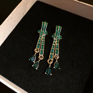 Detail of vintage gold earrings with green crystal teardrop dangles in black box