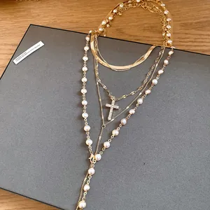 Close-up of multi-layered gold necklace with pearls and rhinestone cross pendant