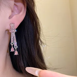 Close-up of elegant pink crystal teardrop earrings worn on model's ear with dark hair