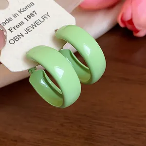 Close-up of glossy light green spray-painted hoop earrings on OBN Jewelry card