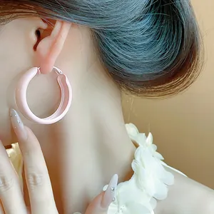 Close-up of minimalist light pink spray-painted hoop earring worn on female model's ear