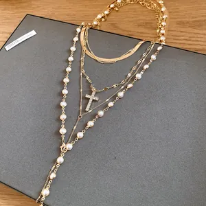 Detailed view of layered gold-tone necklace with pearls and rhinestone cross
