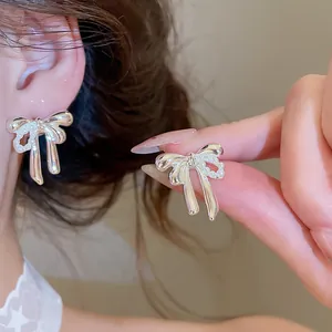 Macro view showing the silver bow texture and pearl settings of the earrings on an ear