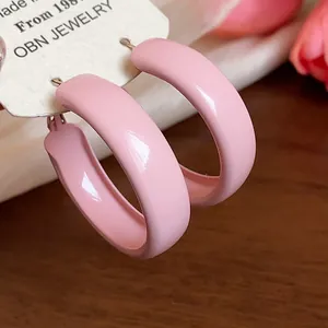 Detail of pink enamel hoop earrings with a smooth spray-painted finish on a display card.