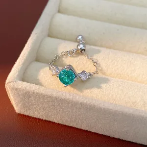 Gros plan sur la pierre de zircon bleu sarcelle et la chaîne réglable de la bague argentée.