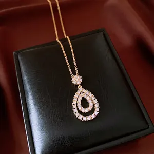 Retro gold-toned double water drop pendant necklace with sparkling zircons on a jewelry box