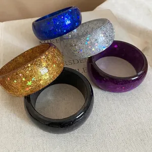 Set of five colorful translucent resin bangles with glittering star sequins on fabric