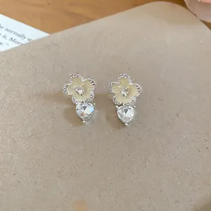 Elegant silver needle stud earrings featuring cream flowers and heart-shaped crystal drops