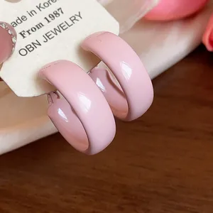 Close-up of glossy baby pink painted hoop earrings presented on an elegant white display card