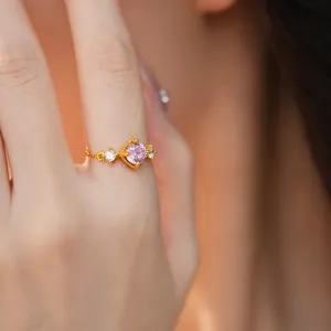 Détail d'une bague dorée ajustable avec pierre de zircon rose de forme carrée