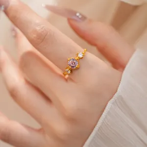 Vue macro détaillée d'une bague réglable plaquée or avec un zircon rose au centre.
