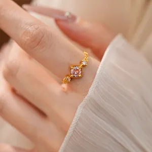 Vue détaillée d'une bague dorée délicate avec un zircon rose carré au centre.