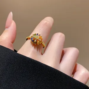 Close-up of a luxury gold flower ring with colorful gemstones on an index finger.