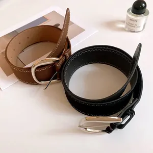 Detailed view of stylish black and brown leather belts with decorative white stitching